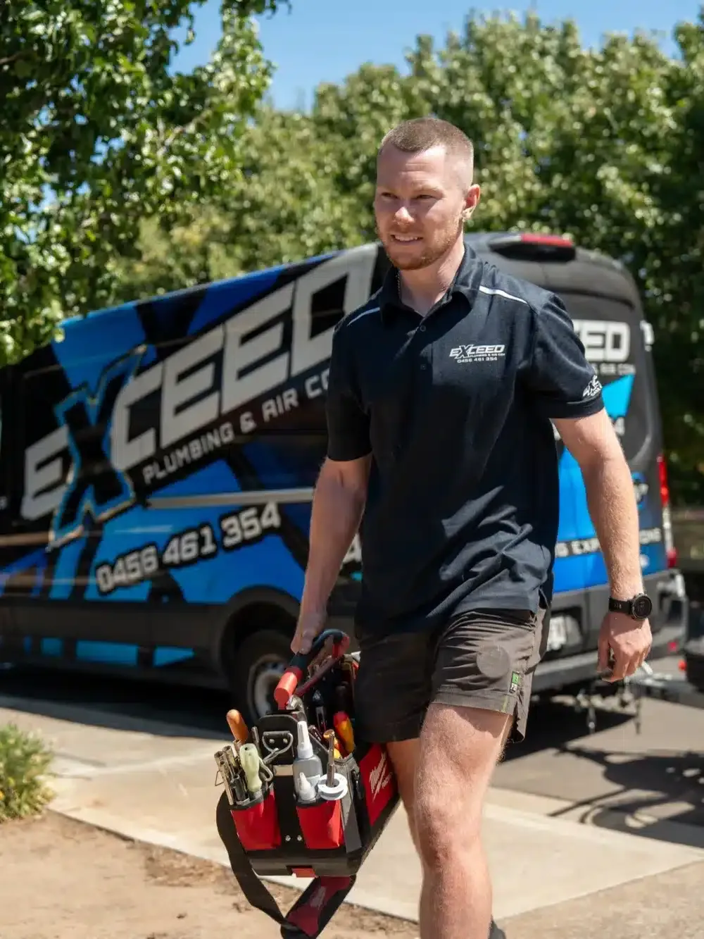 Caleb John of Exceed Plumbing walking up from the service van with his tool bag