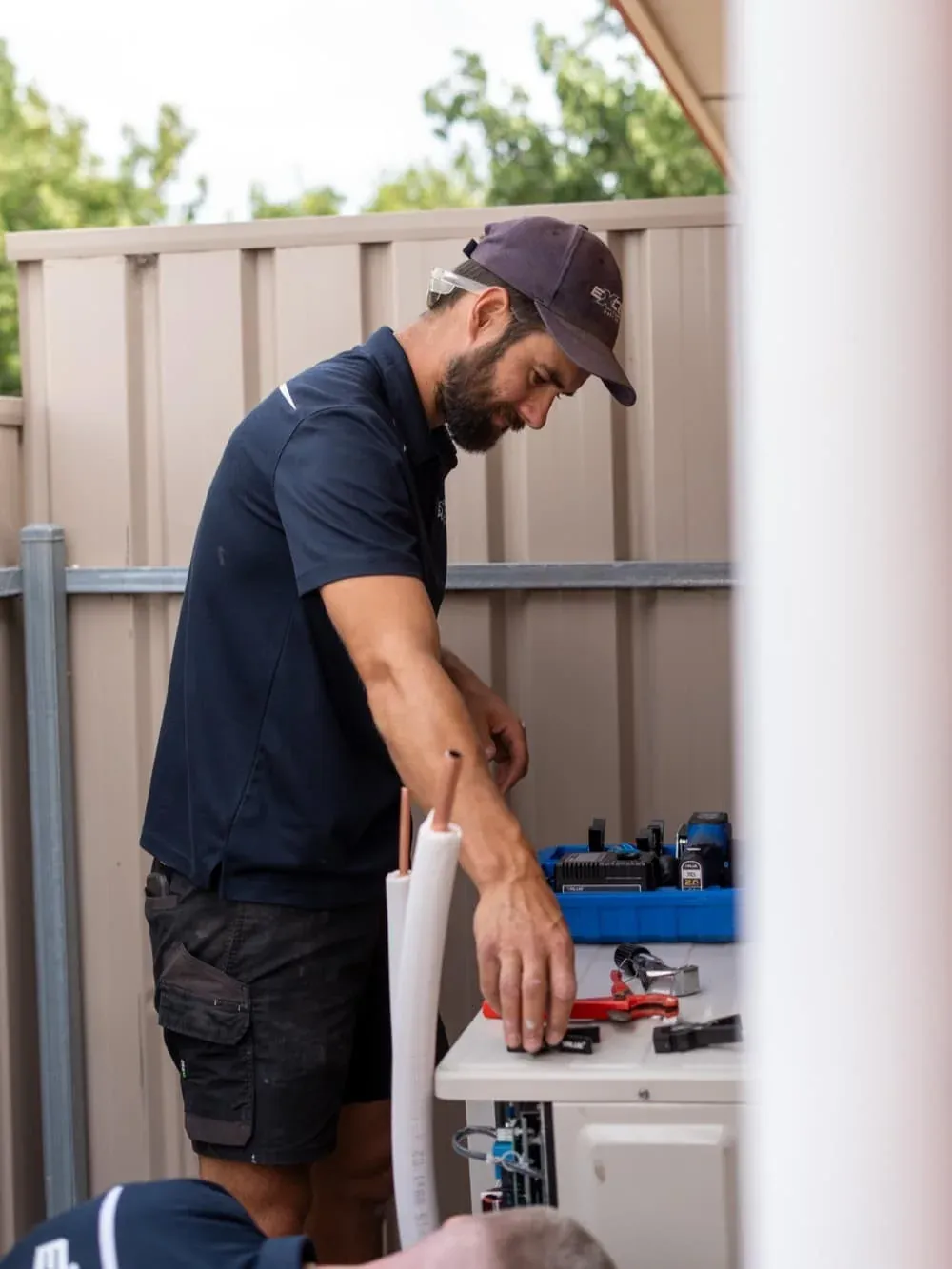 Exceed Plumbing technician working on the pipework at an air conditioner outdoor unit