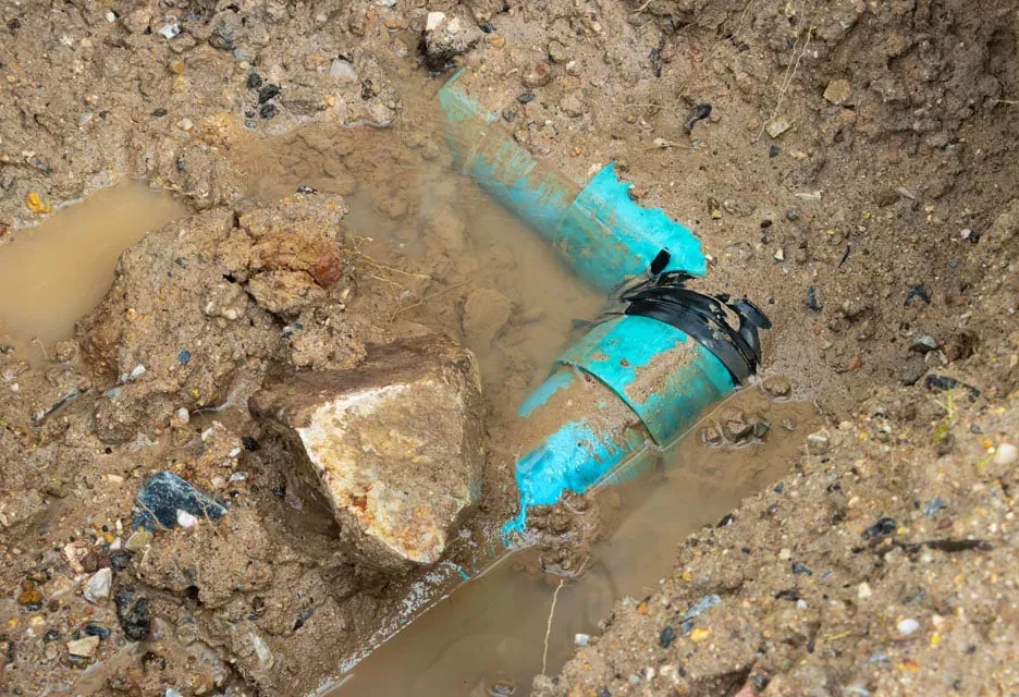 Broken drain pipe dug up in wet, muddy ground
