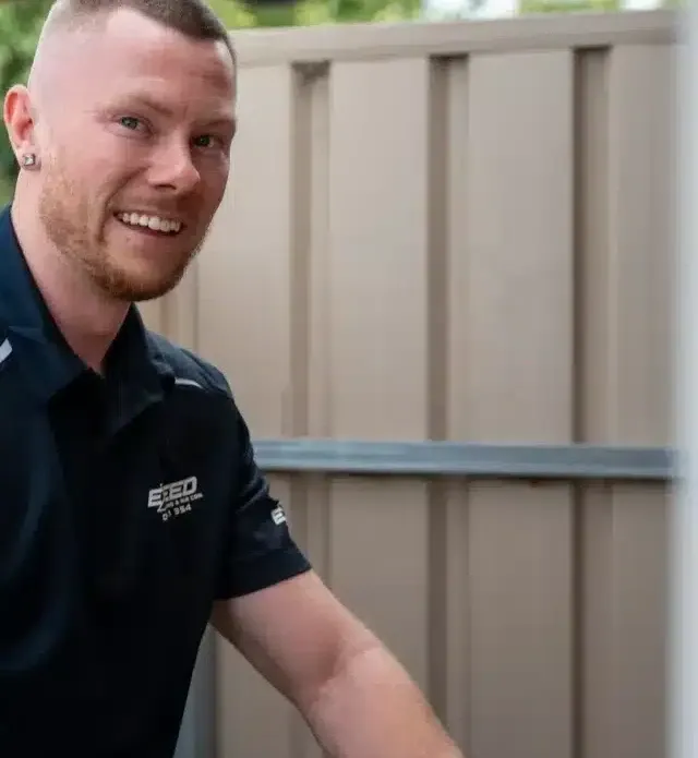 Caleb John, owner of Exceed Plumbing, smiling on a job