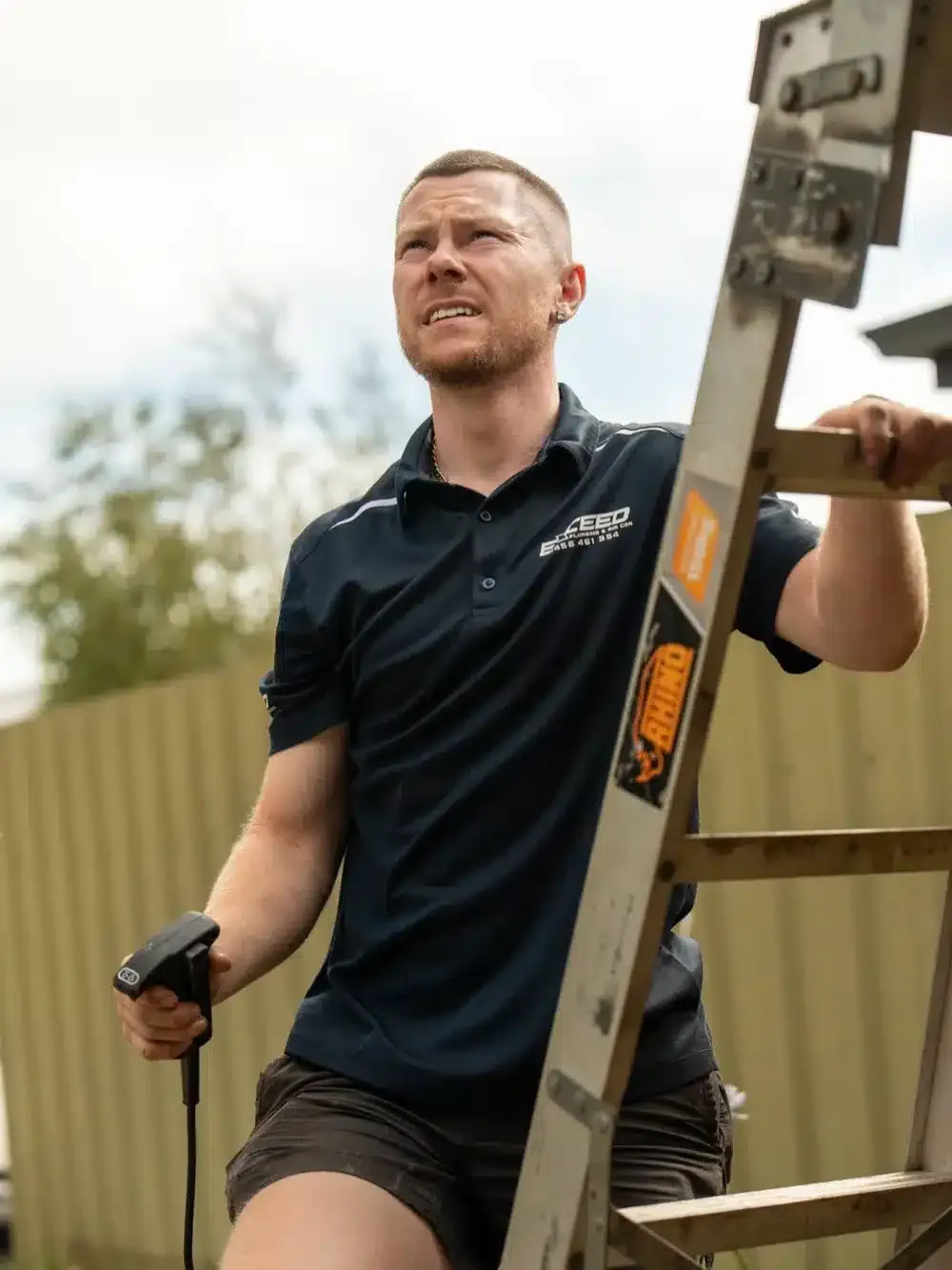 Caleb John of Exceed Plumbing climbing a ladder to a job