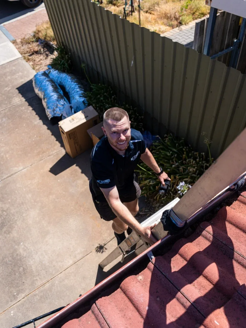 Exceed Plumbing technician at the roof edge, ready to climb up for a ducted air conditioning job