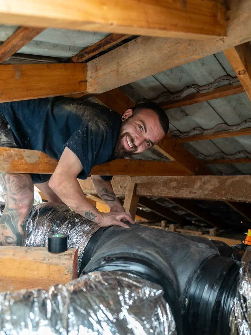 Exceed Plumbing technician in a roof space beside new ducted air conditioning ducts