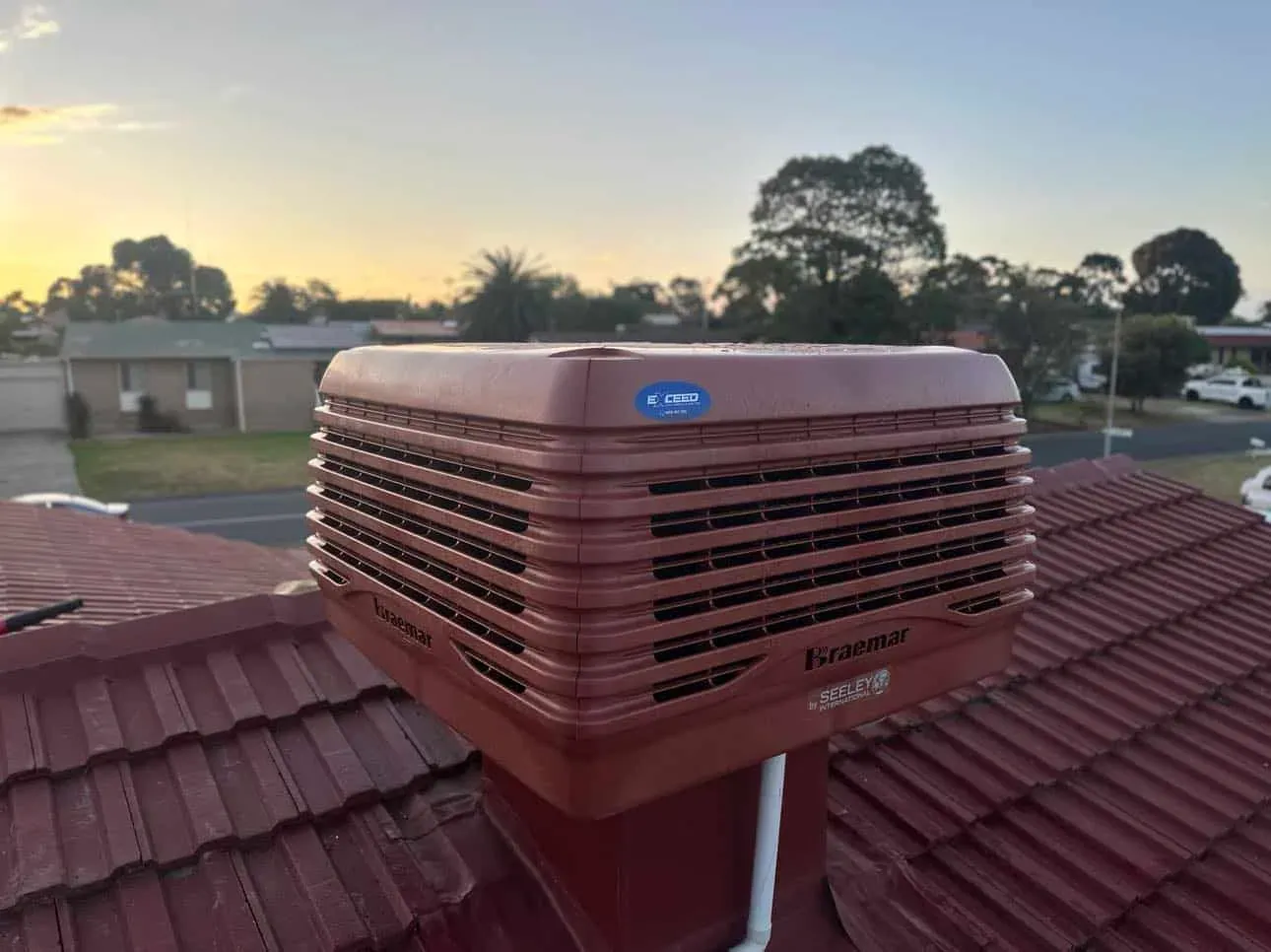 Evaporative cooler on a tiled roof at dusk