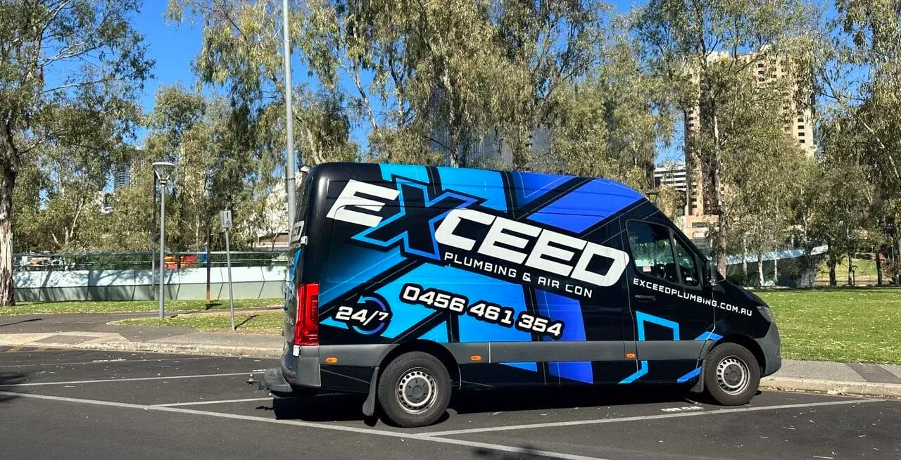 The Exceed Plumbing van parked beside the Adelaide parklands, the city behind it