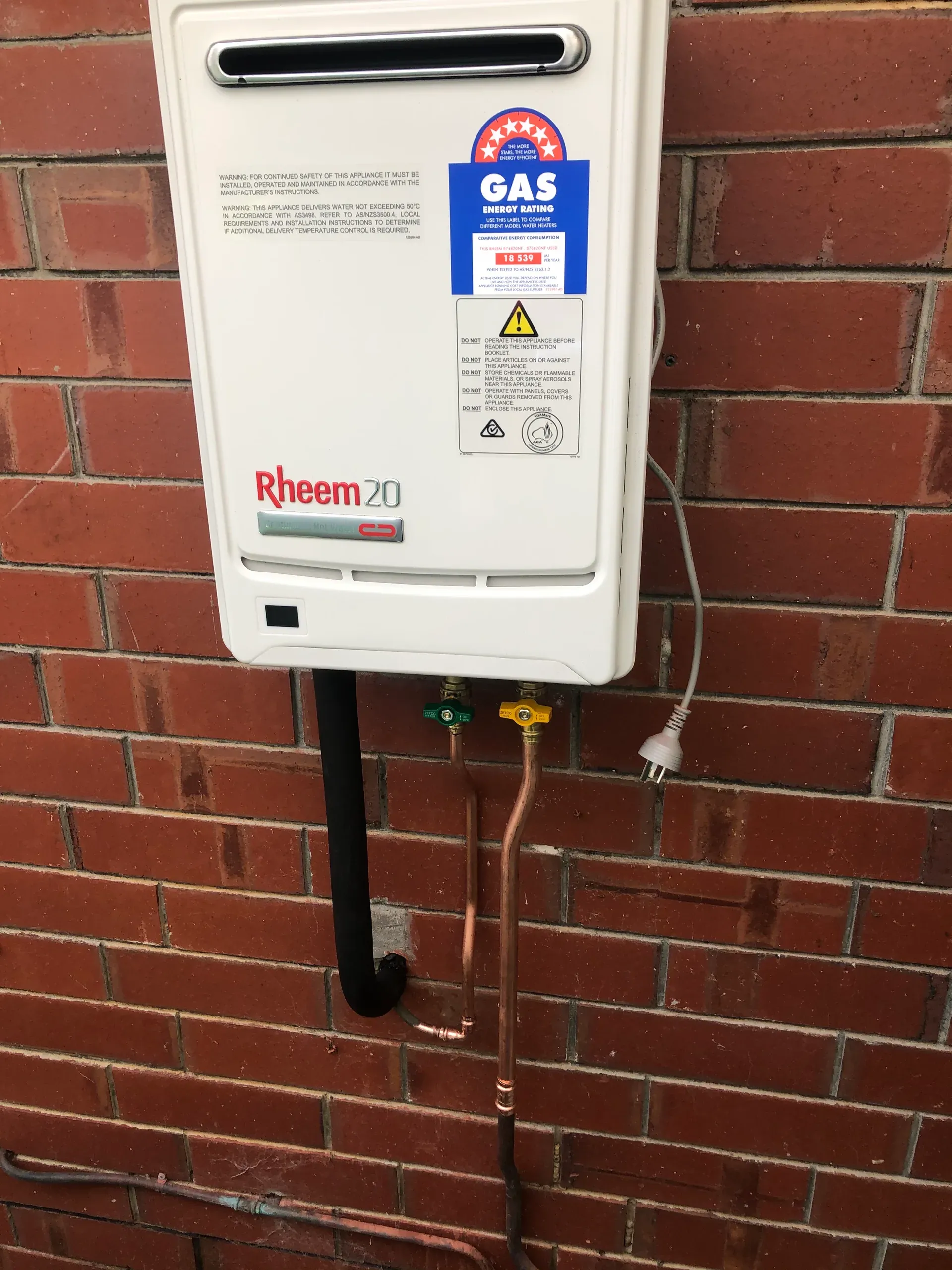 Gas continuous flow hot water unit installed on a brick wall