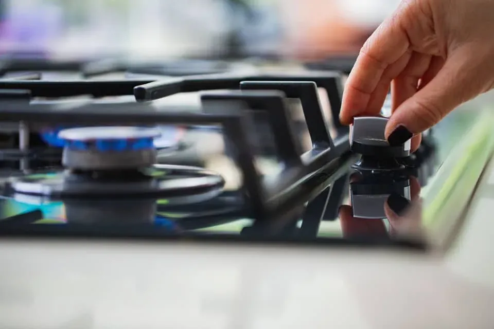 Hand turning a gas cooktop control knob