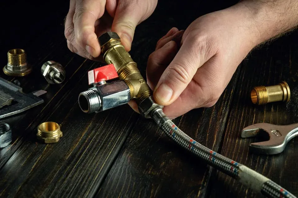 Hands fitting a braided water hose to a brass isolating valve
