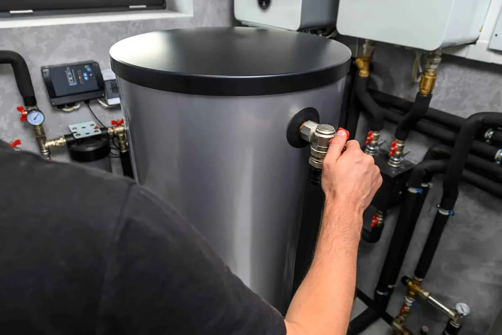 Hand tightening a valve on a hot water storage tank