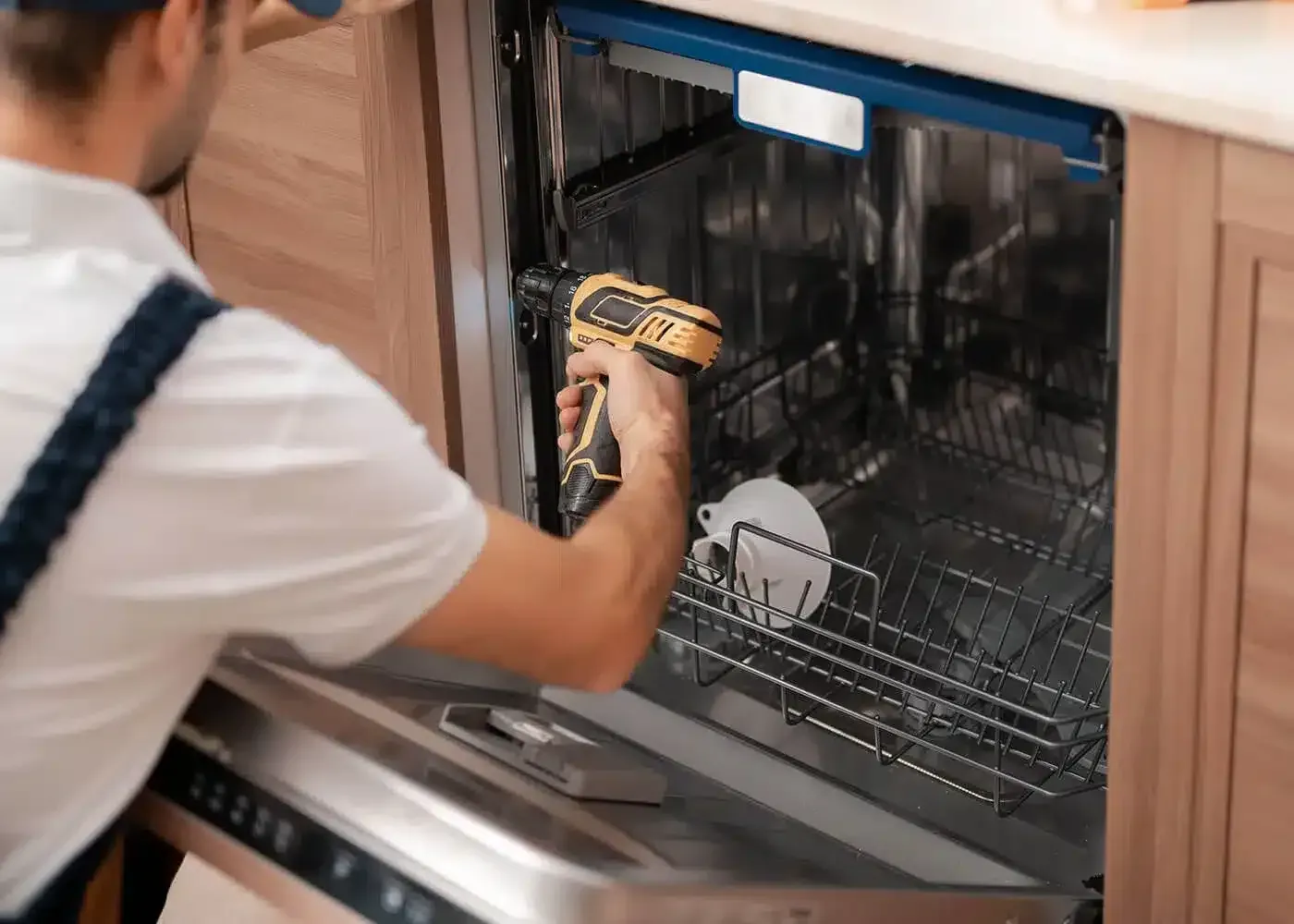 Installer fixing a built-in dishwasher into its cabinet
