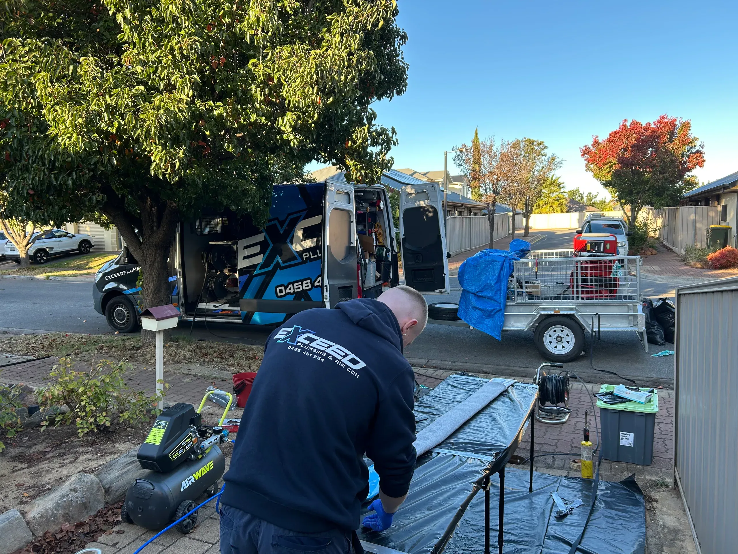Exceed Plumbing plumber working at the relining bench beside the service van