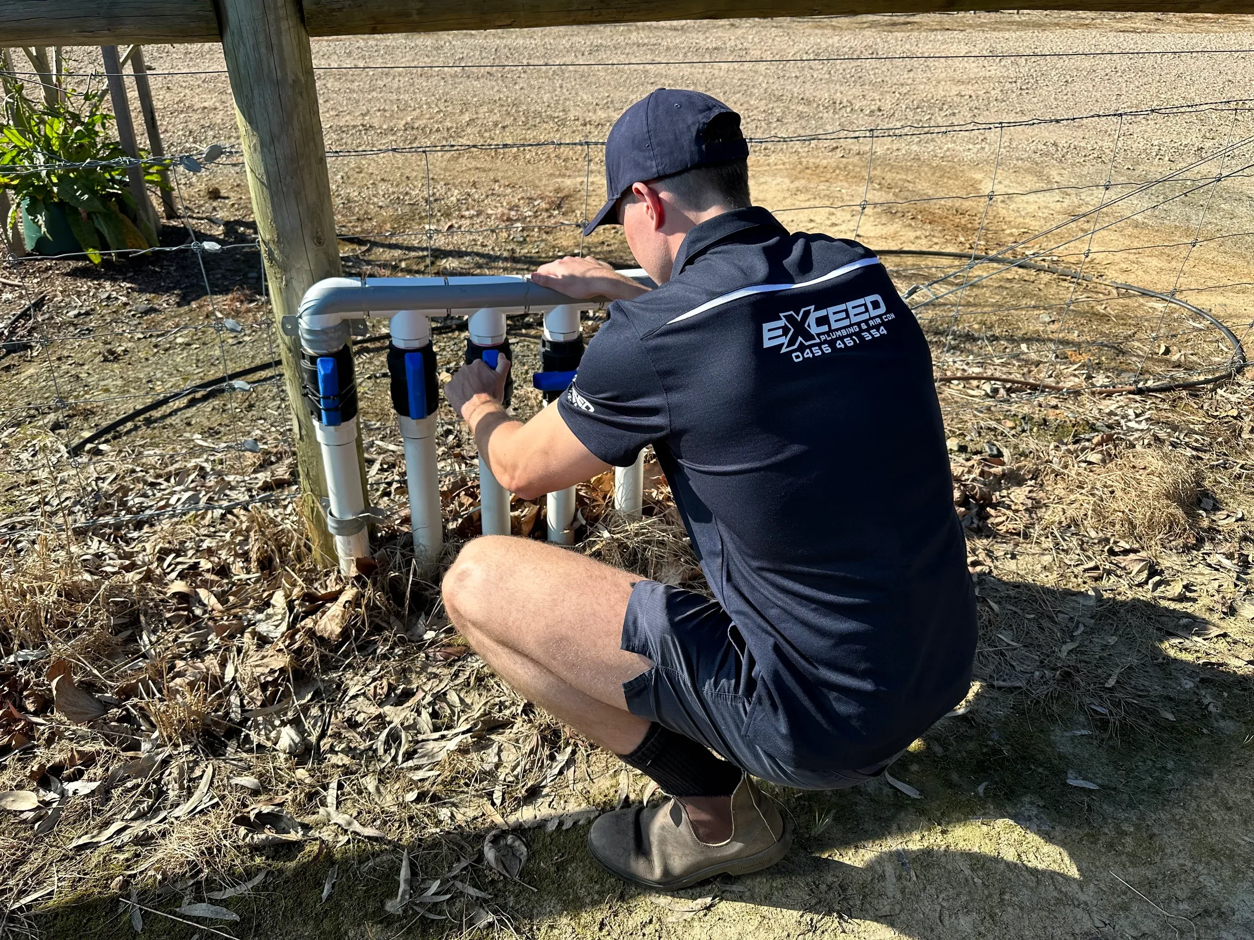 Exceed Plumbing plumber checking water pipes and valves in a backyard