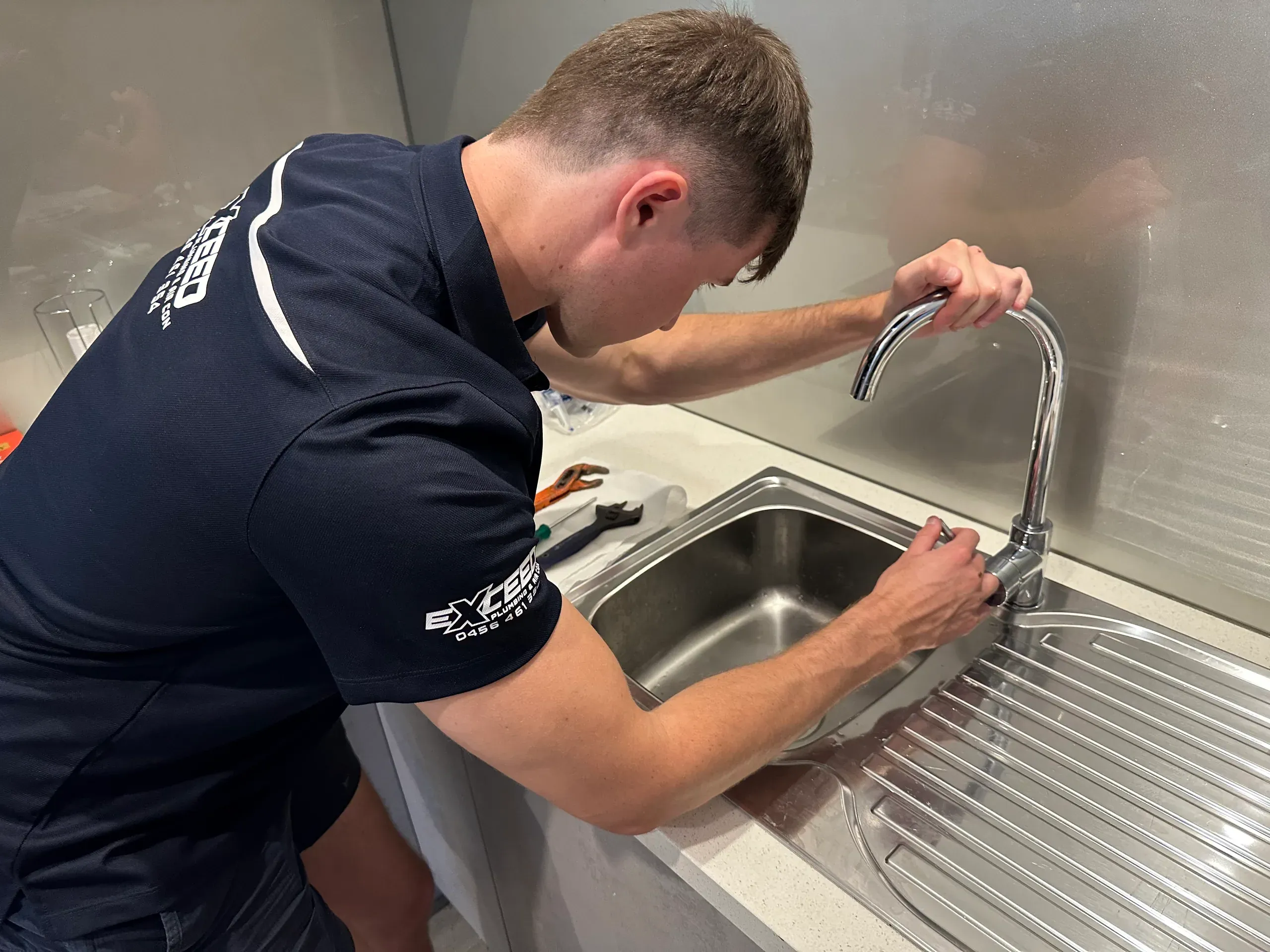 Exceed Plumbing plumber fixing a kitchen mixer tap