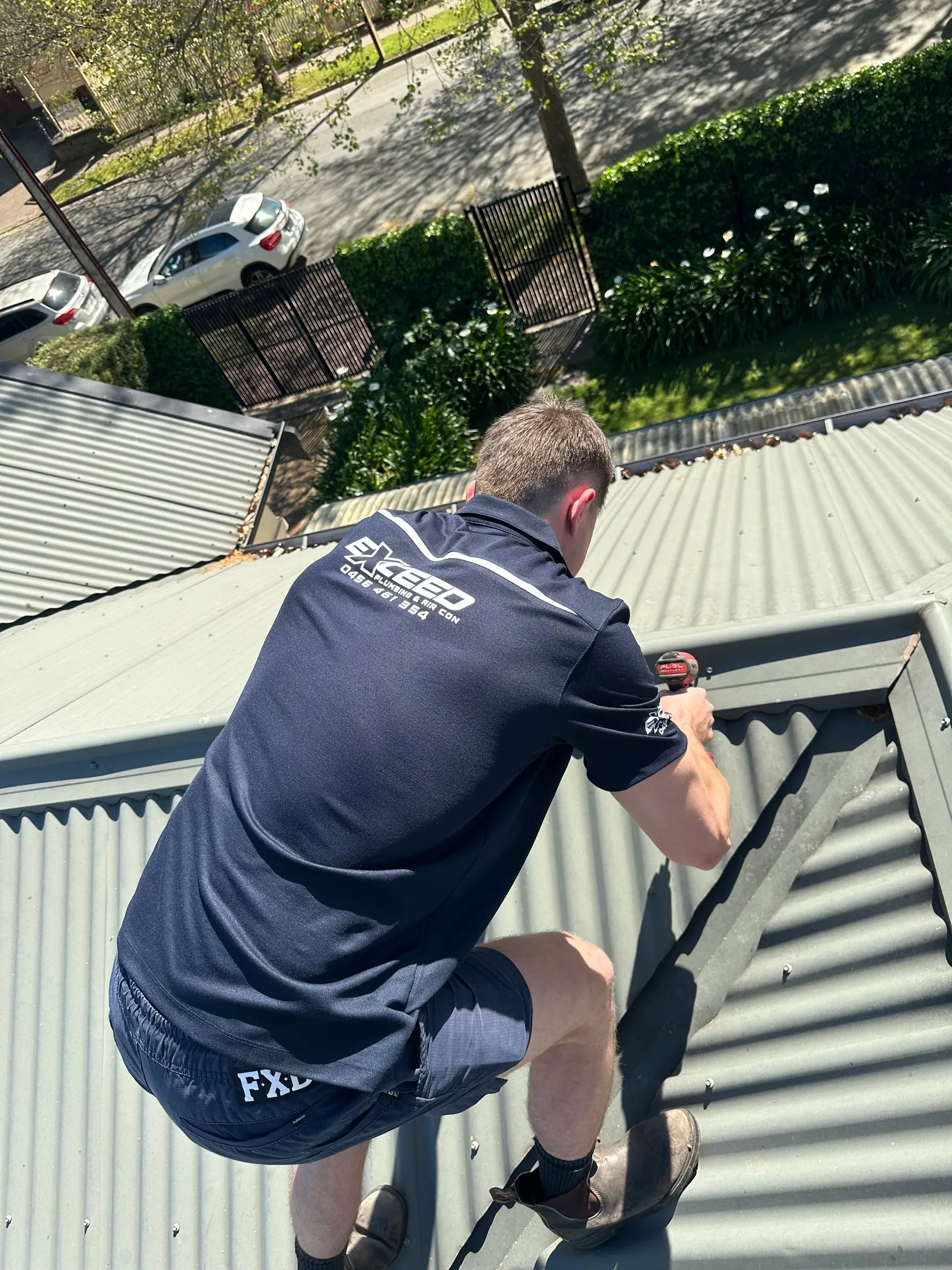 Exceed Plumbing plumber working along the ridge of a metal roof