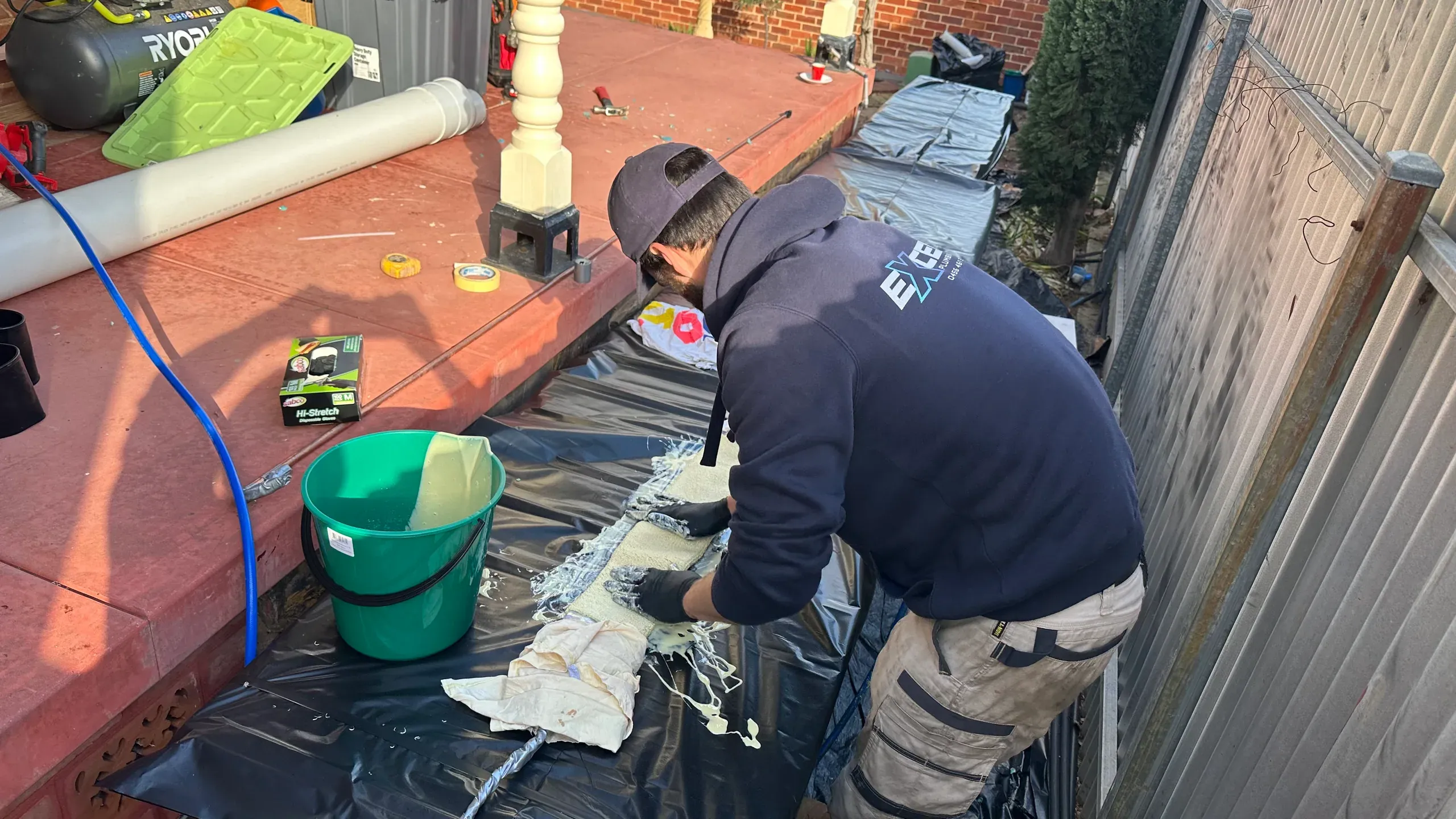Exceed Plumbing plumber preparing a pipe relining liner on a ground sheet