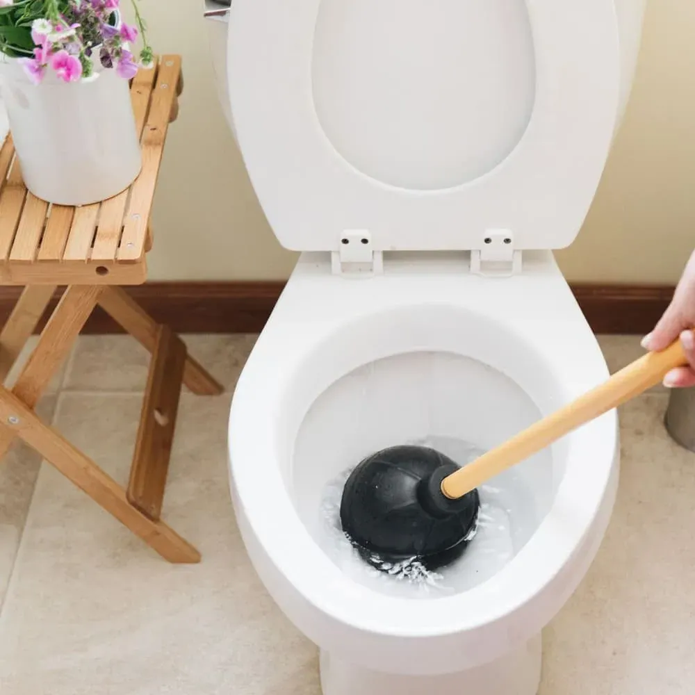 Plunger in a blocked toilet bowl