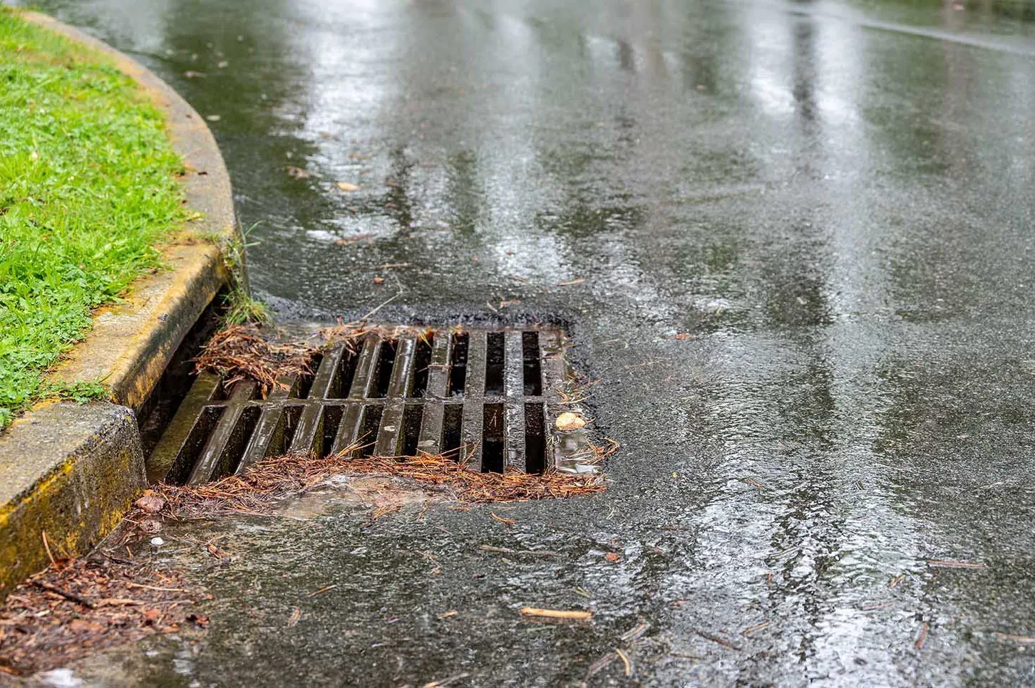 Street stormwater grate taking run-off in the rain