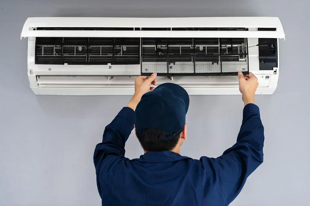 Technician fitting the indoor unit of a split system air conditioner to a wall