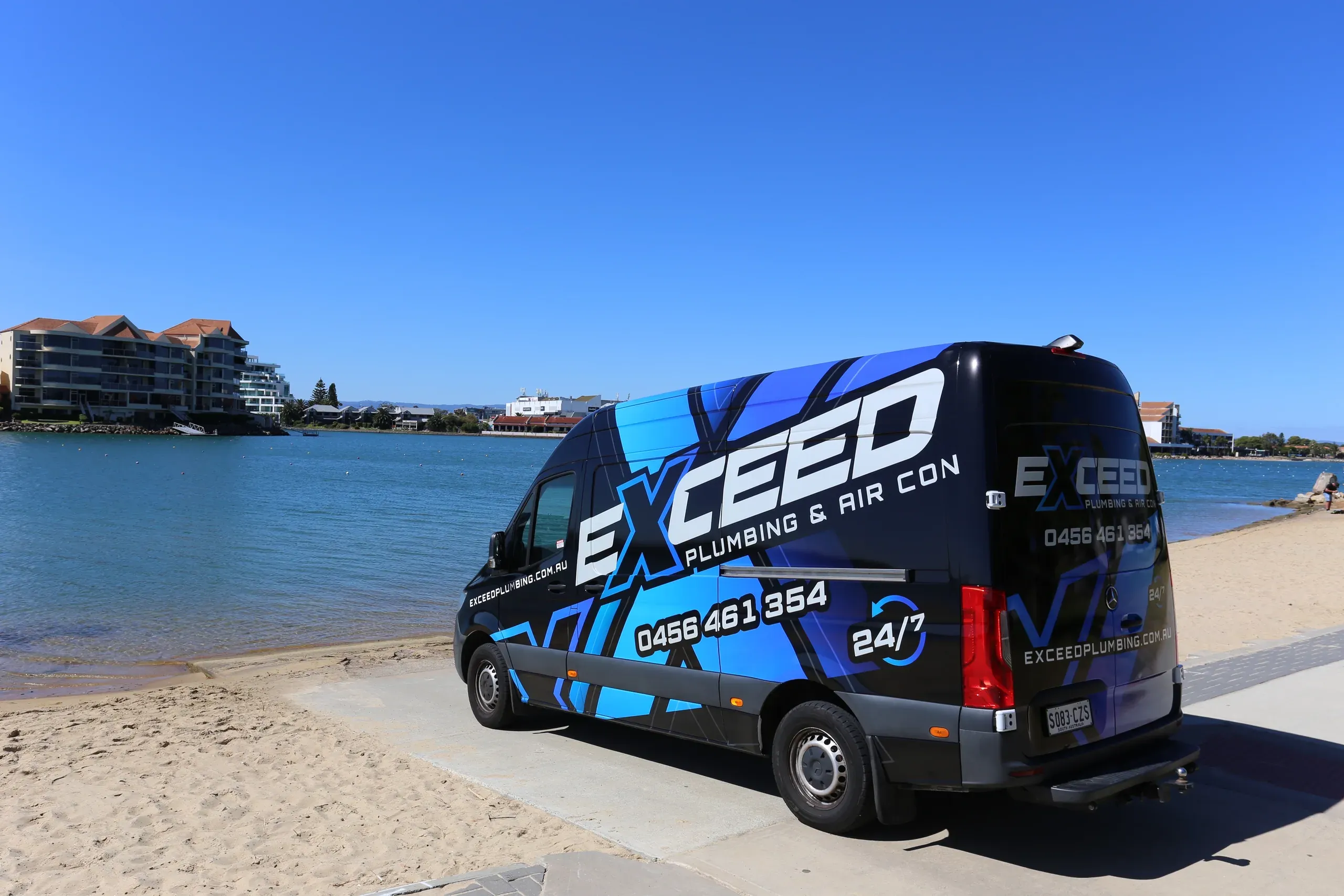 The Exceed Plumbing van parked on the shore of the lake at West Lakes
