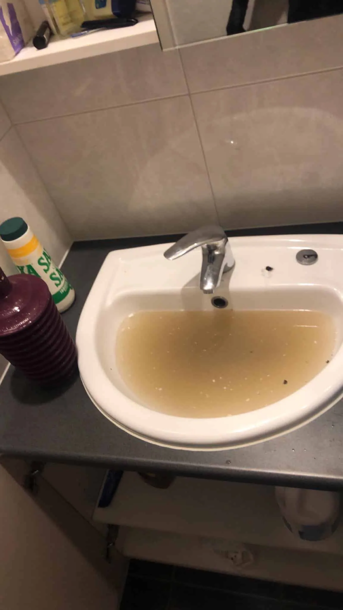 Blocked bathroom basin full of dirty water