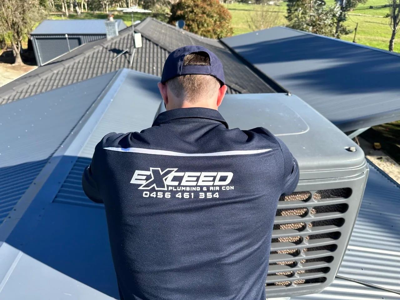 Exceed Plumbing plumber servicing an evaporative cooler on a roof