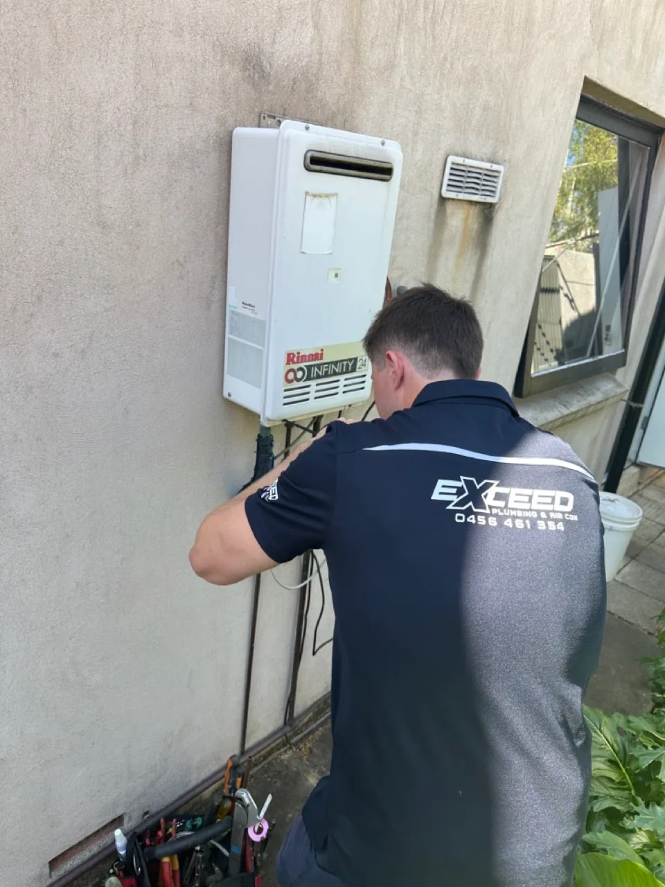 Exceed Plumbing plumber servicing a Rinnai continuous flow hot water unit