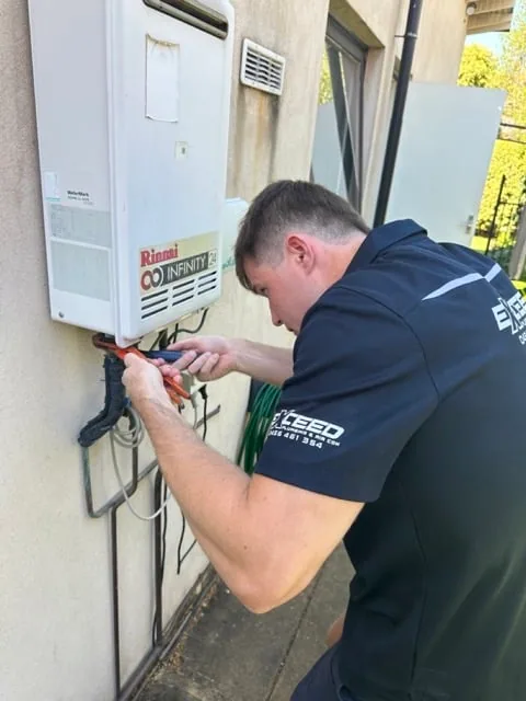 Exceed Plumbing plumber wiring a Rinnai continuous flow hot water unit