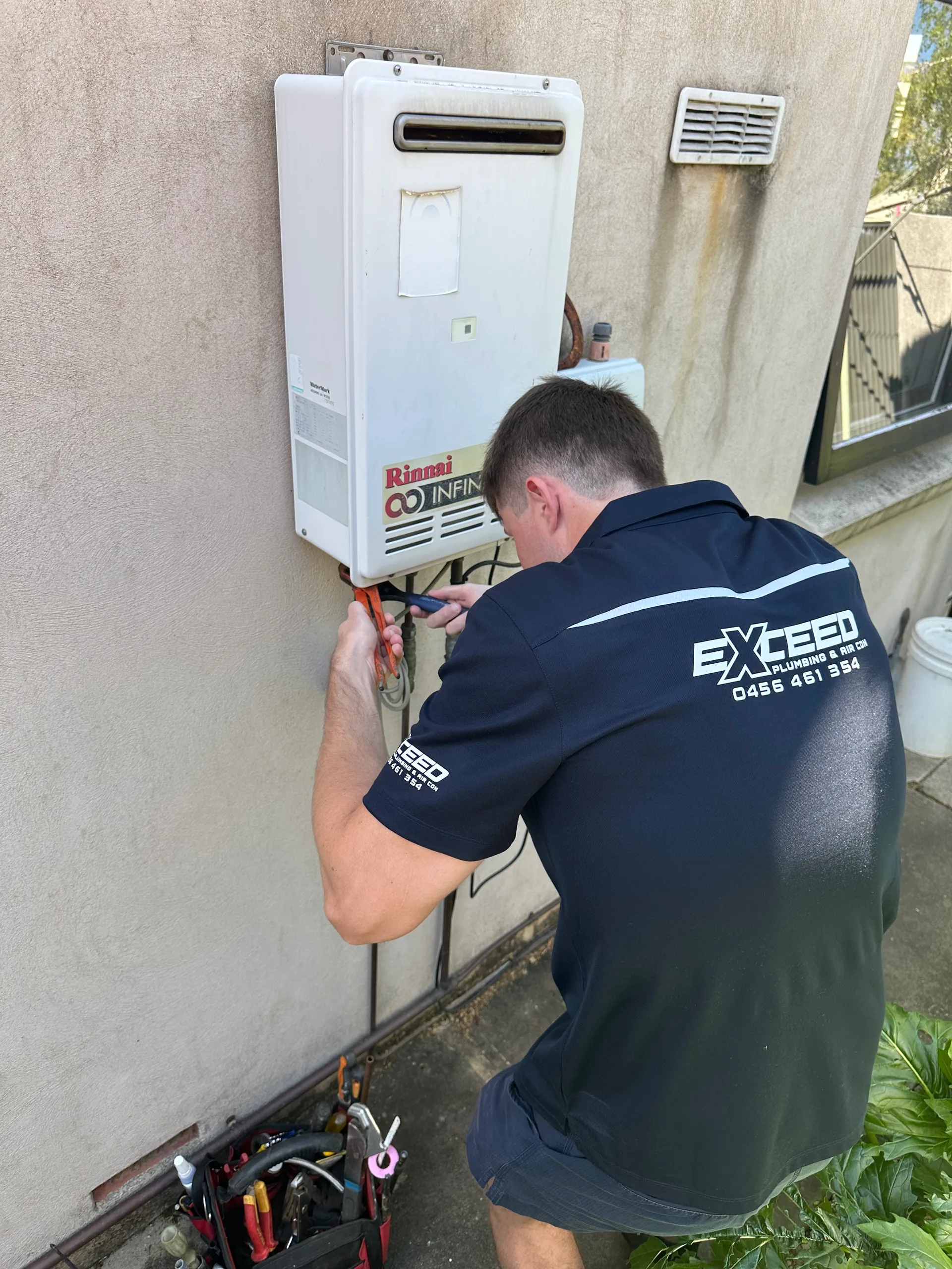 Exceed Plumbing plumber working on the connections of a continuous flow hot water unit