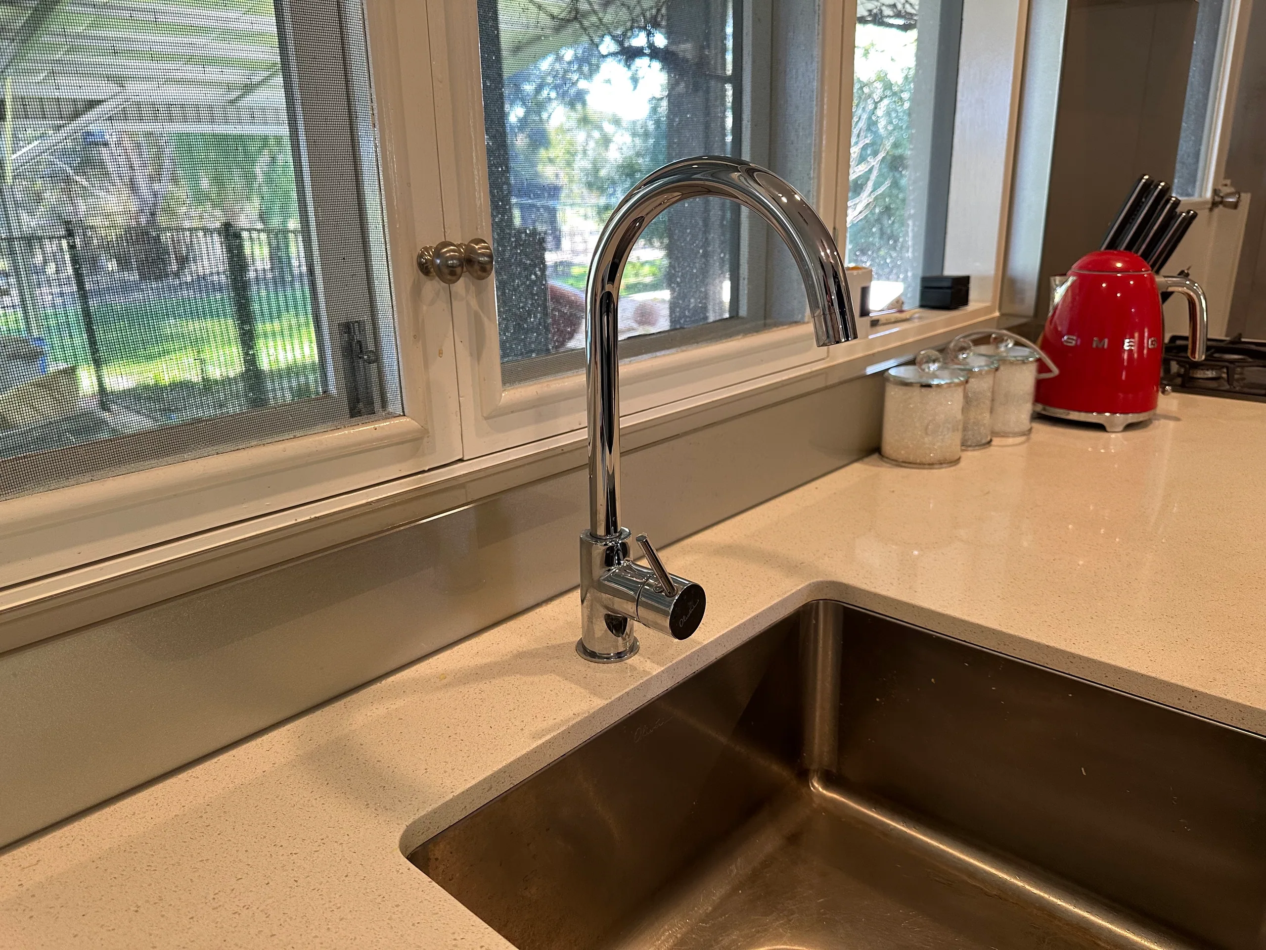 Kitchen sink with a gooseneck mixer tap under a window