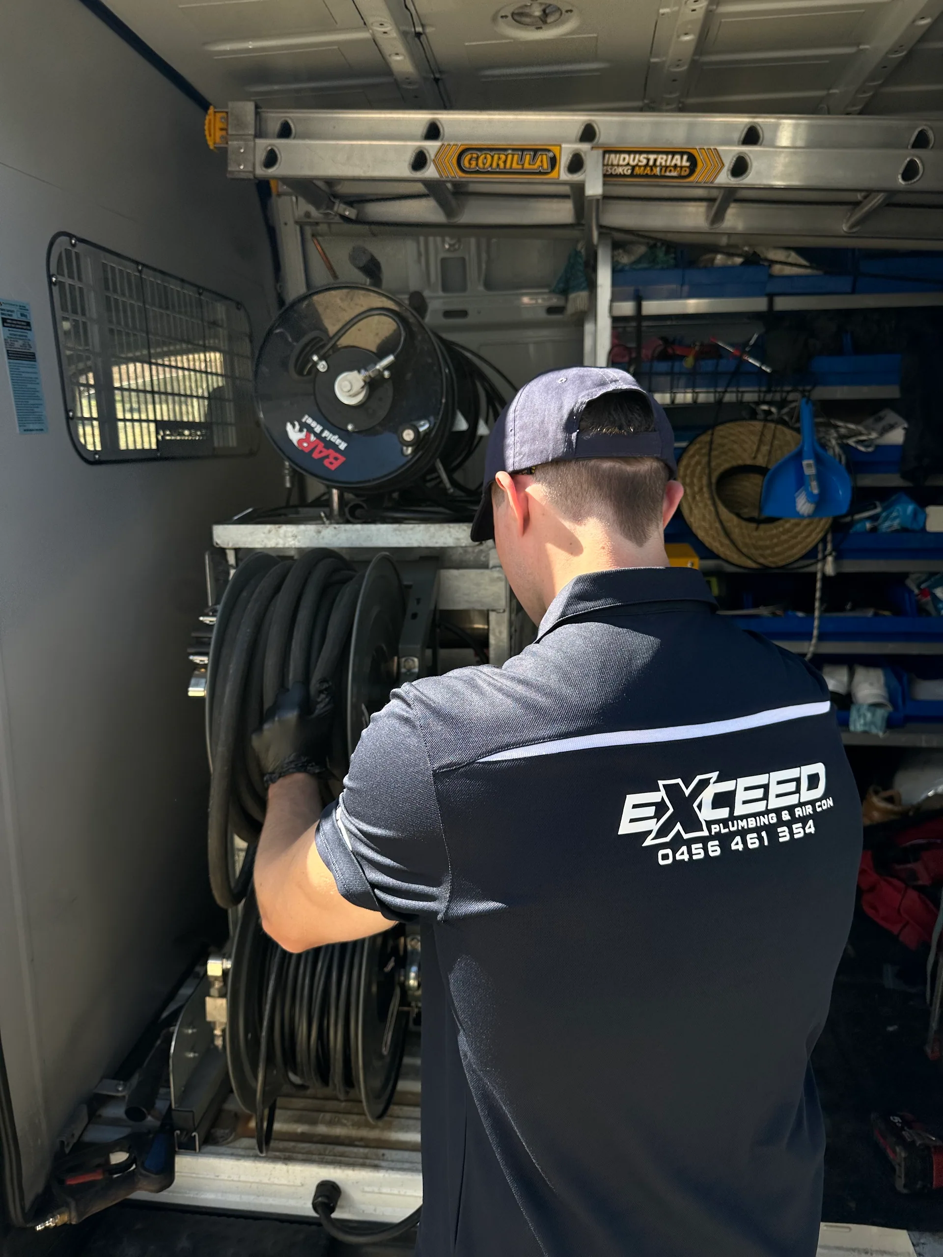 Exceed Plumbing plumber at the equipment racking in a work van
