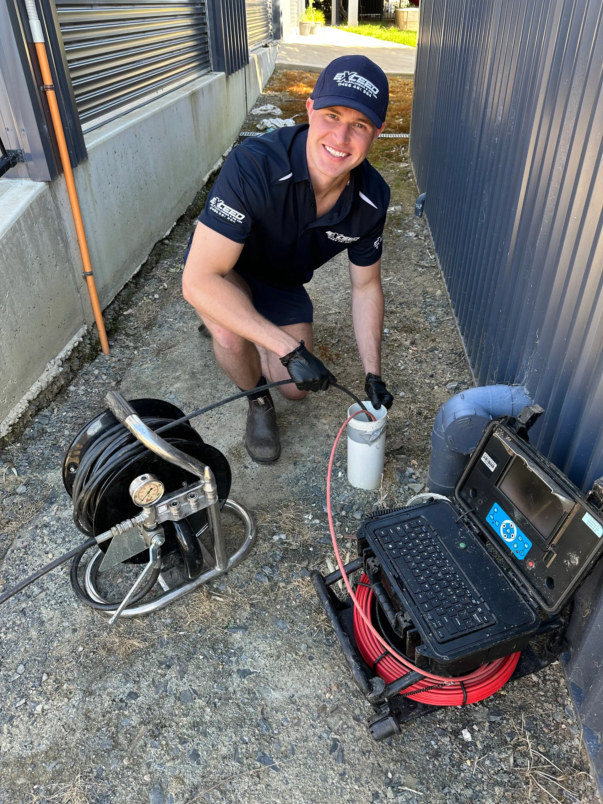 Exceed Plumbing plumber with a drain camera and cable reel in a side passage