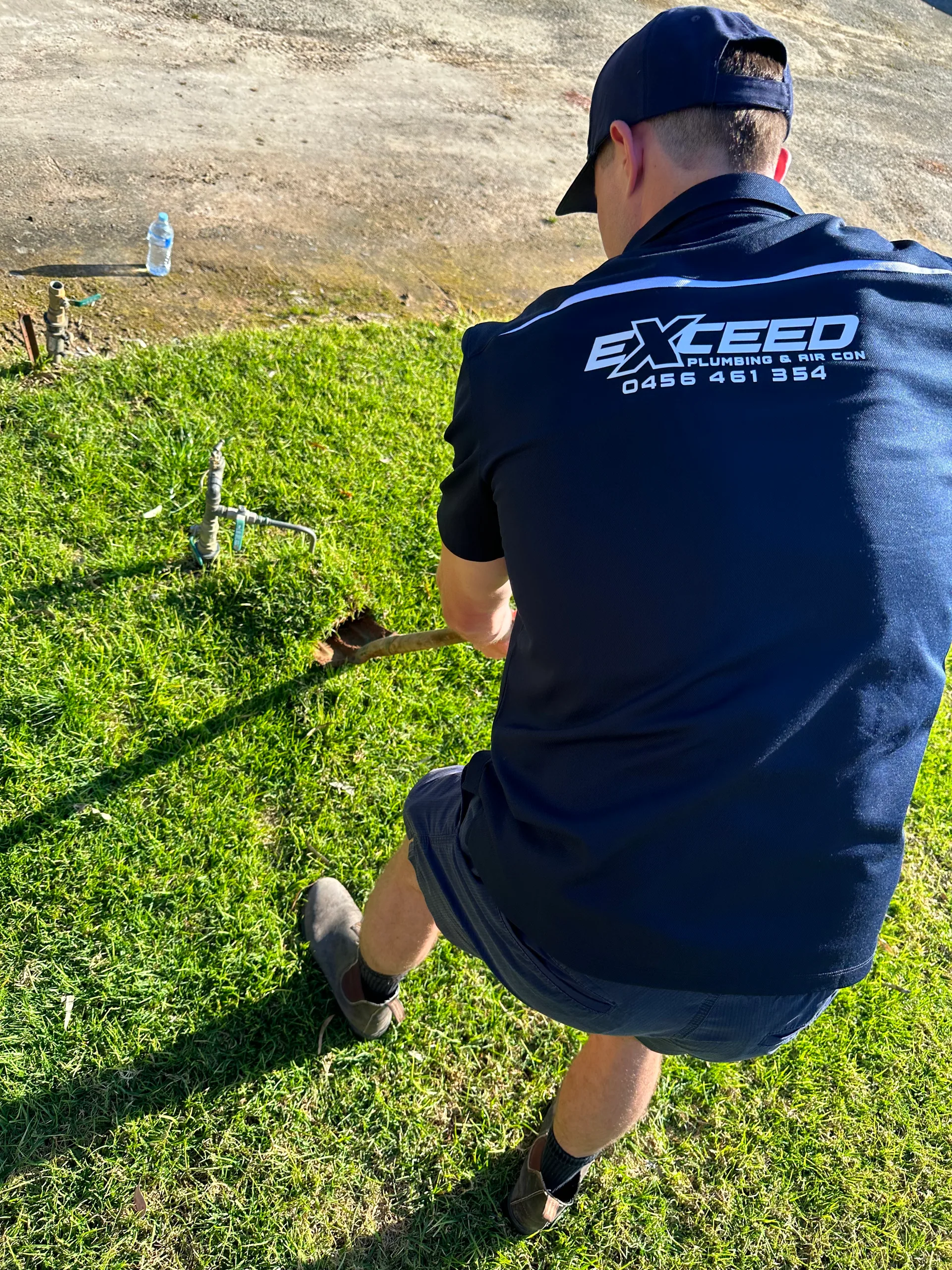 Exceed Plumbing plumber digging around a garden tap