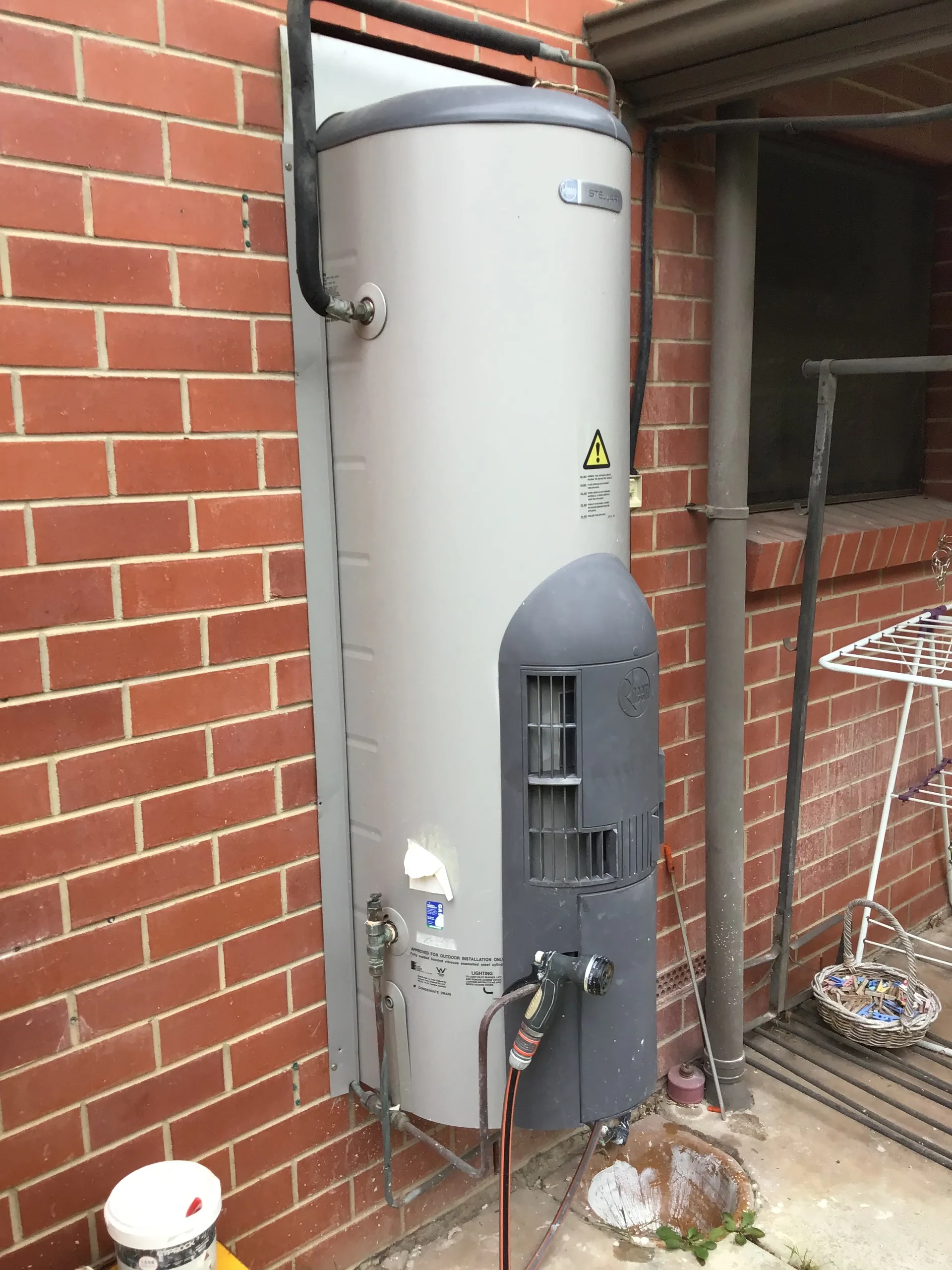Gas storage hot water system against a red brick wall
