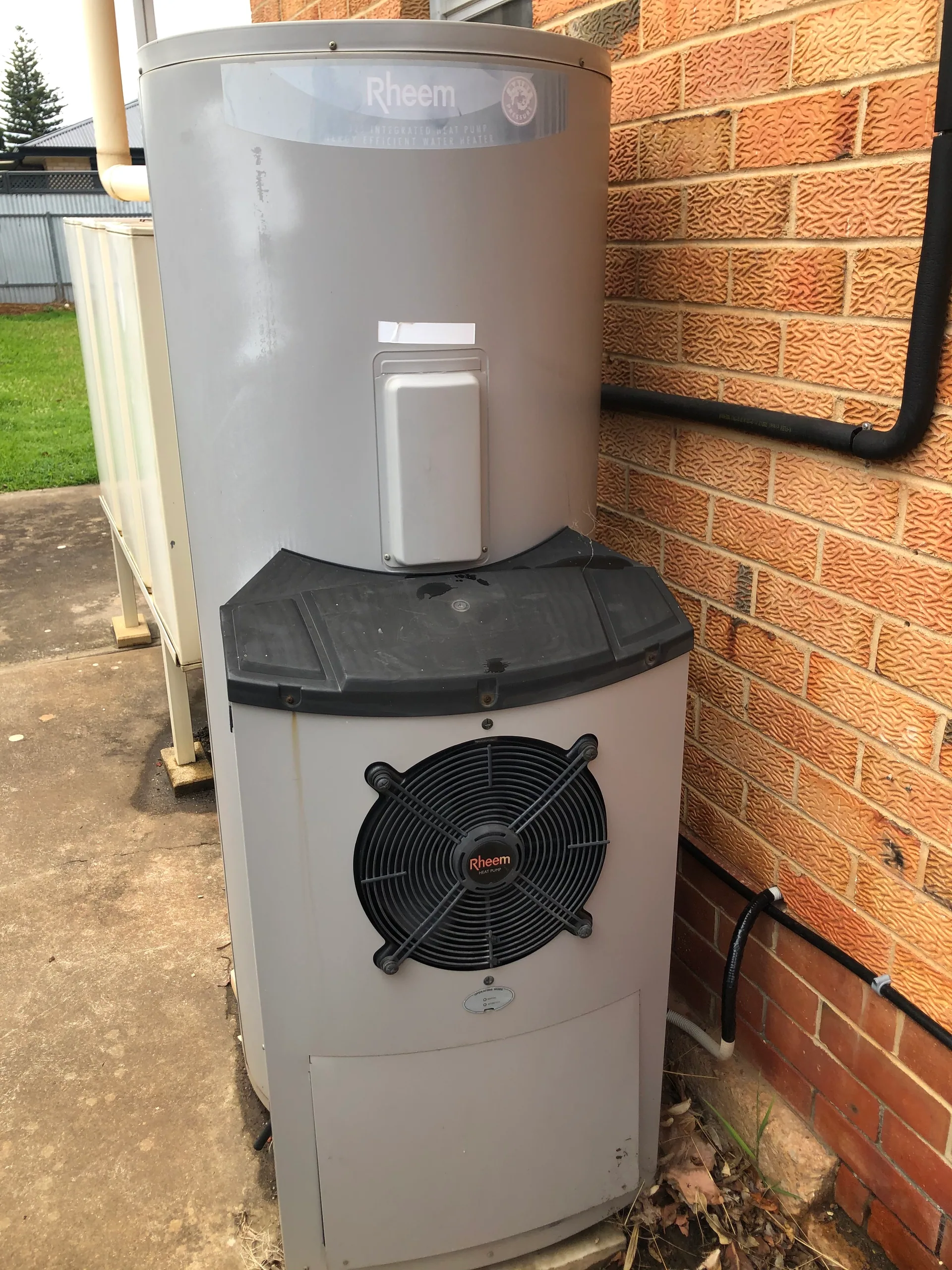 Rheem heat pump hot water system beside a brick wall