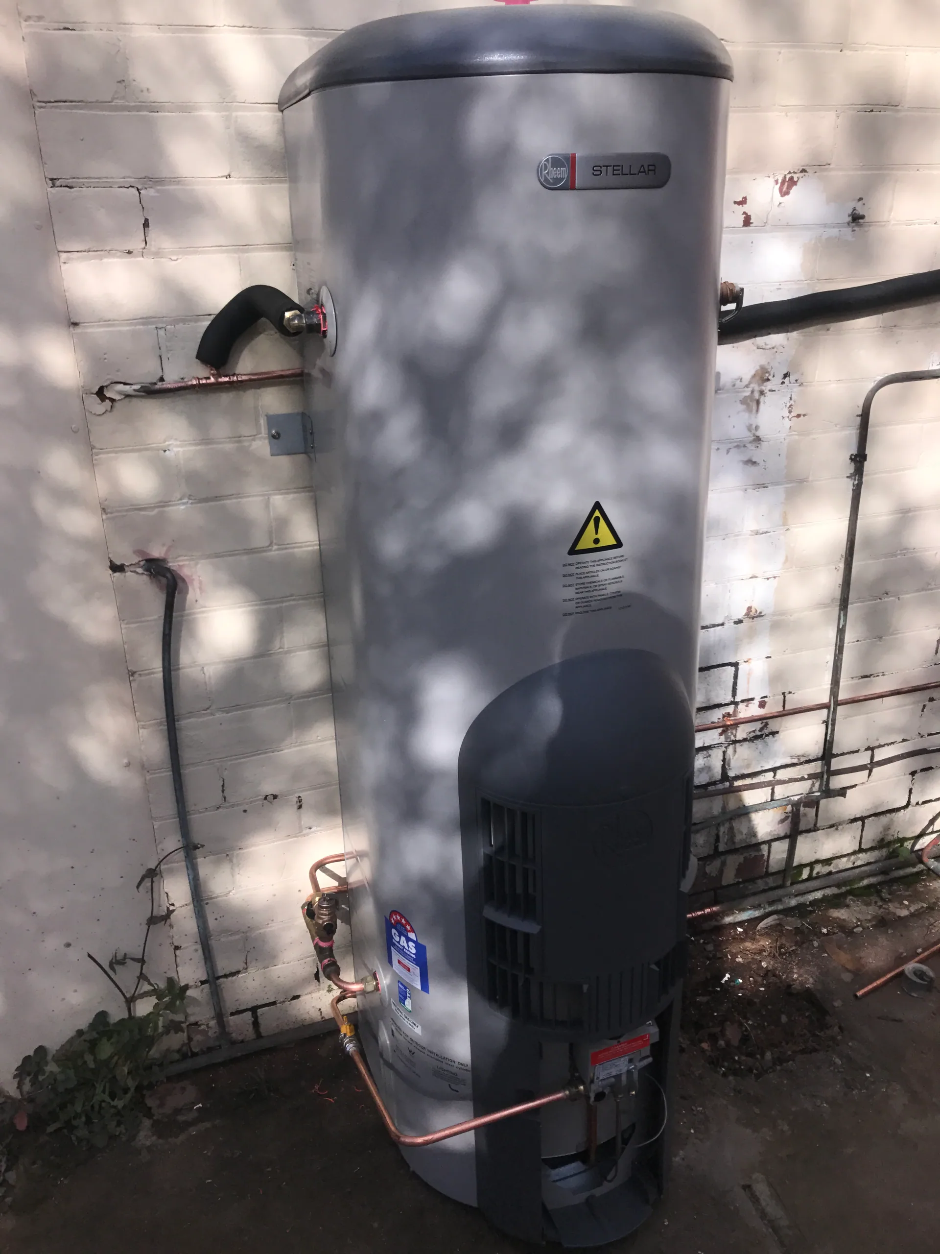 Gas storage hot water system against a painted brick wall