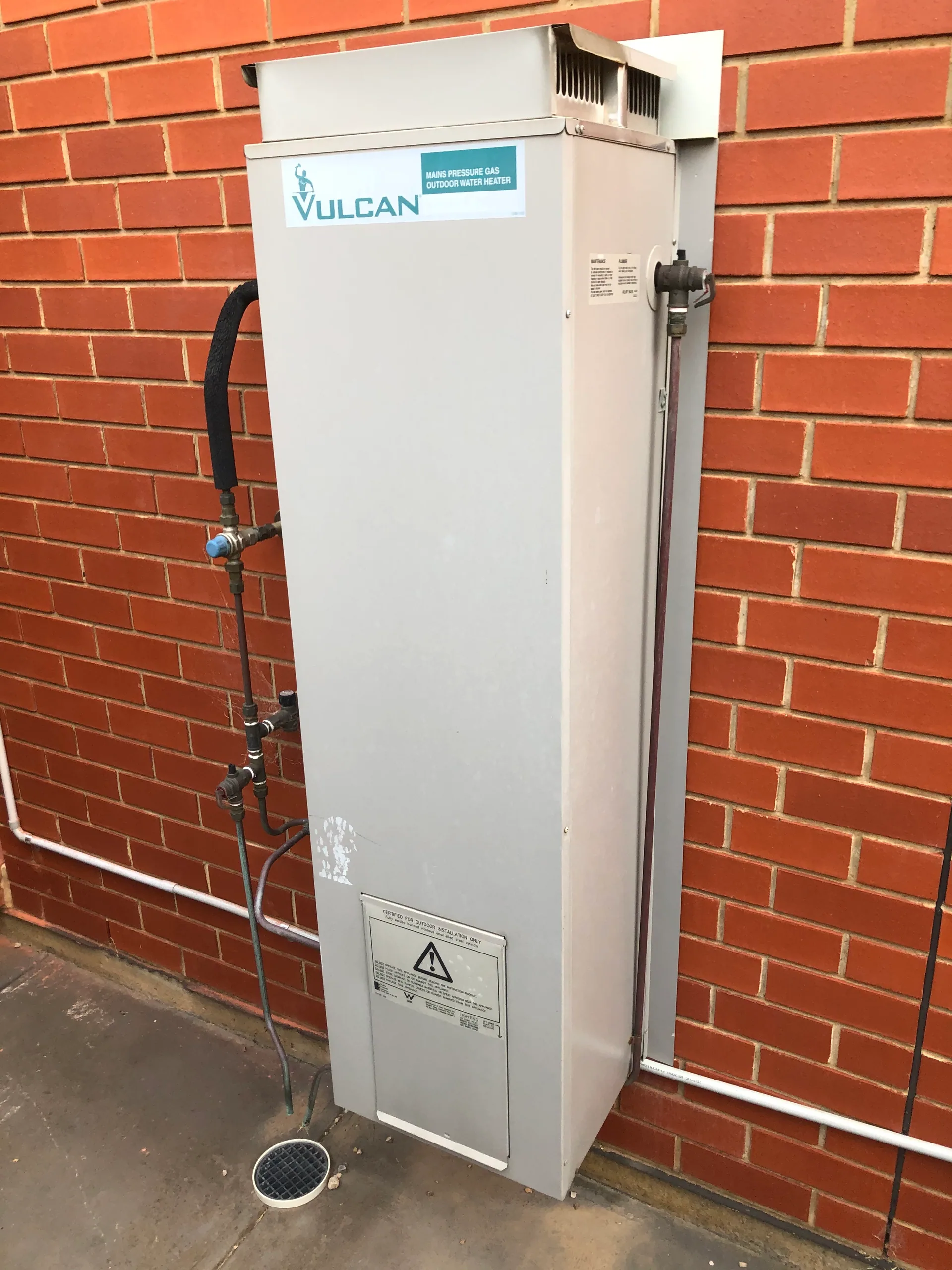 Vulcan gas hot water system on a red brick wall