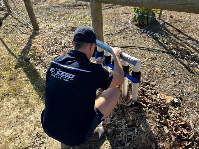 Exceed Plumbing plumber working on a PVC pipe manifold with blue valves