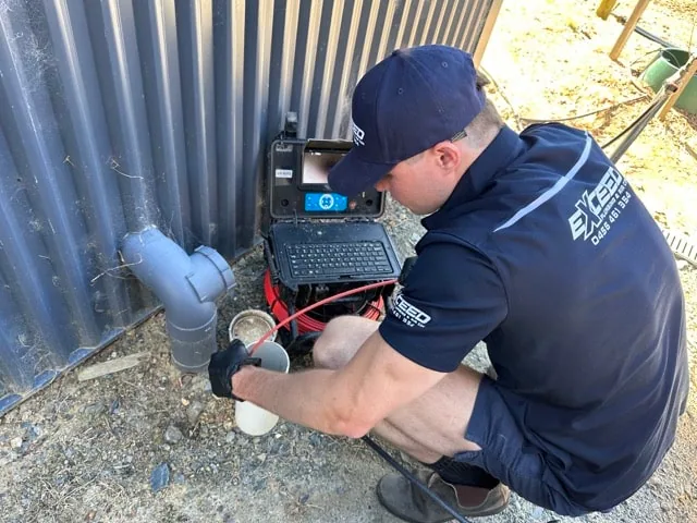 Exceed Plumbing plumber feeding a drain camera into a stormwater pipe