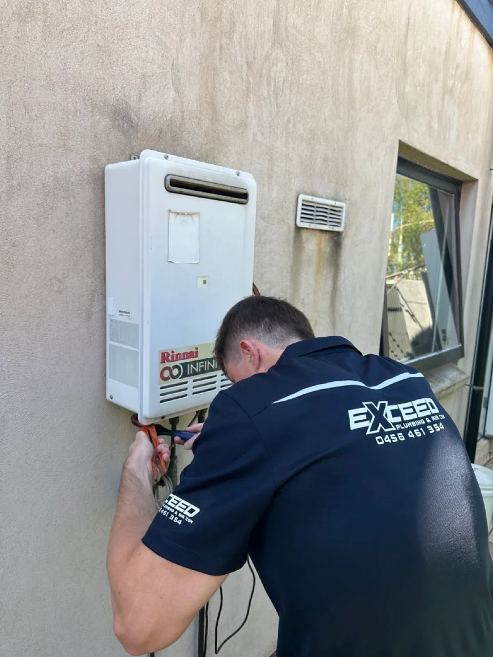 Exceed Plumbing plumber working on a Rinnai continuous flow hot water unit