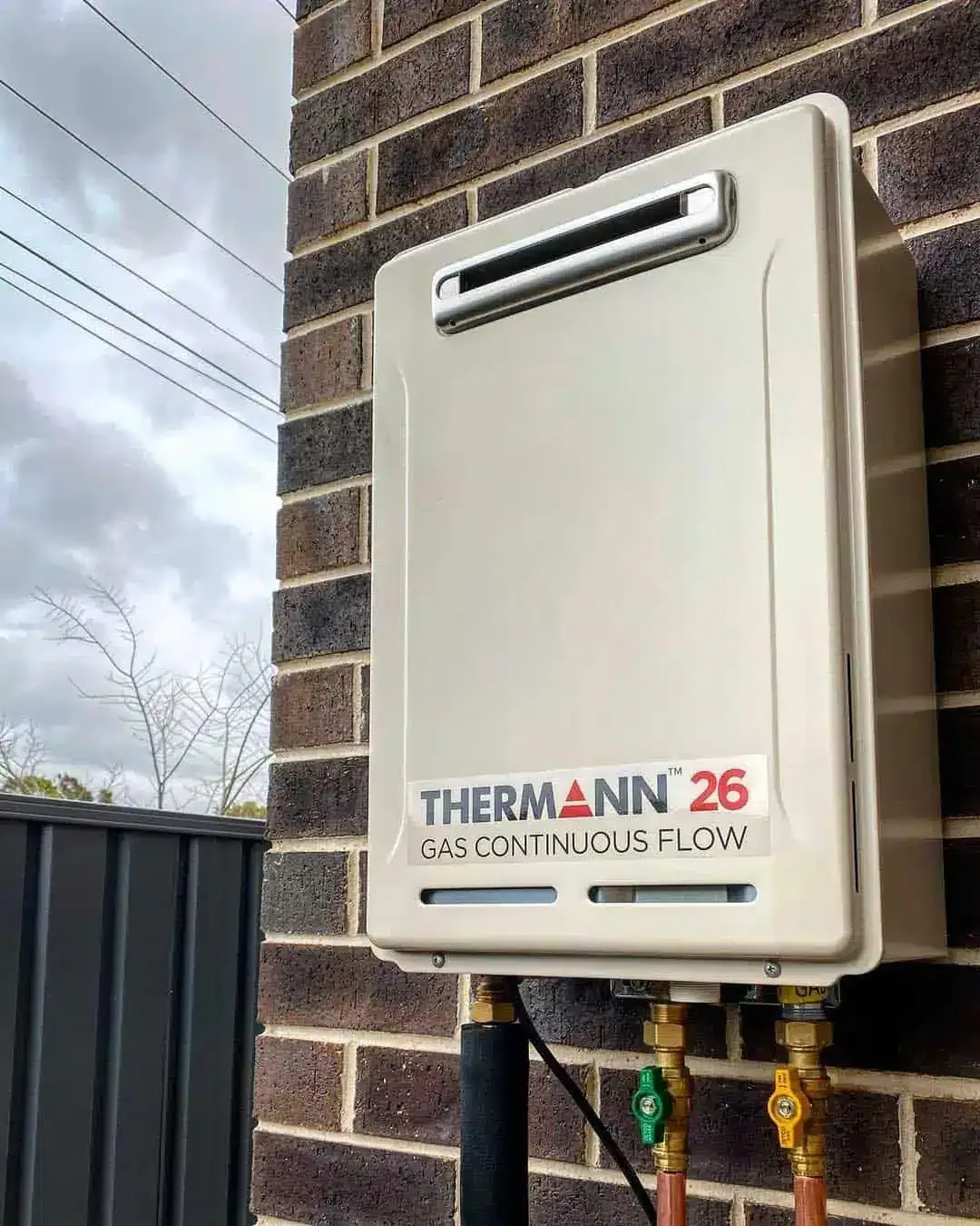 A Thermann 26 gas continuous flow hot water system on a brick wall
