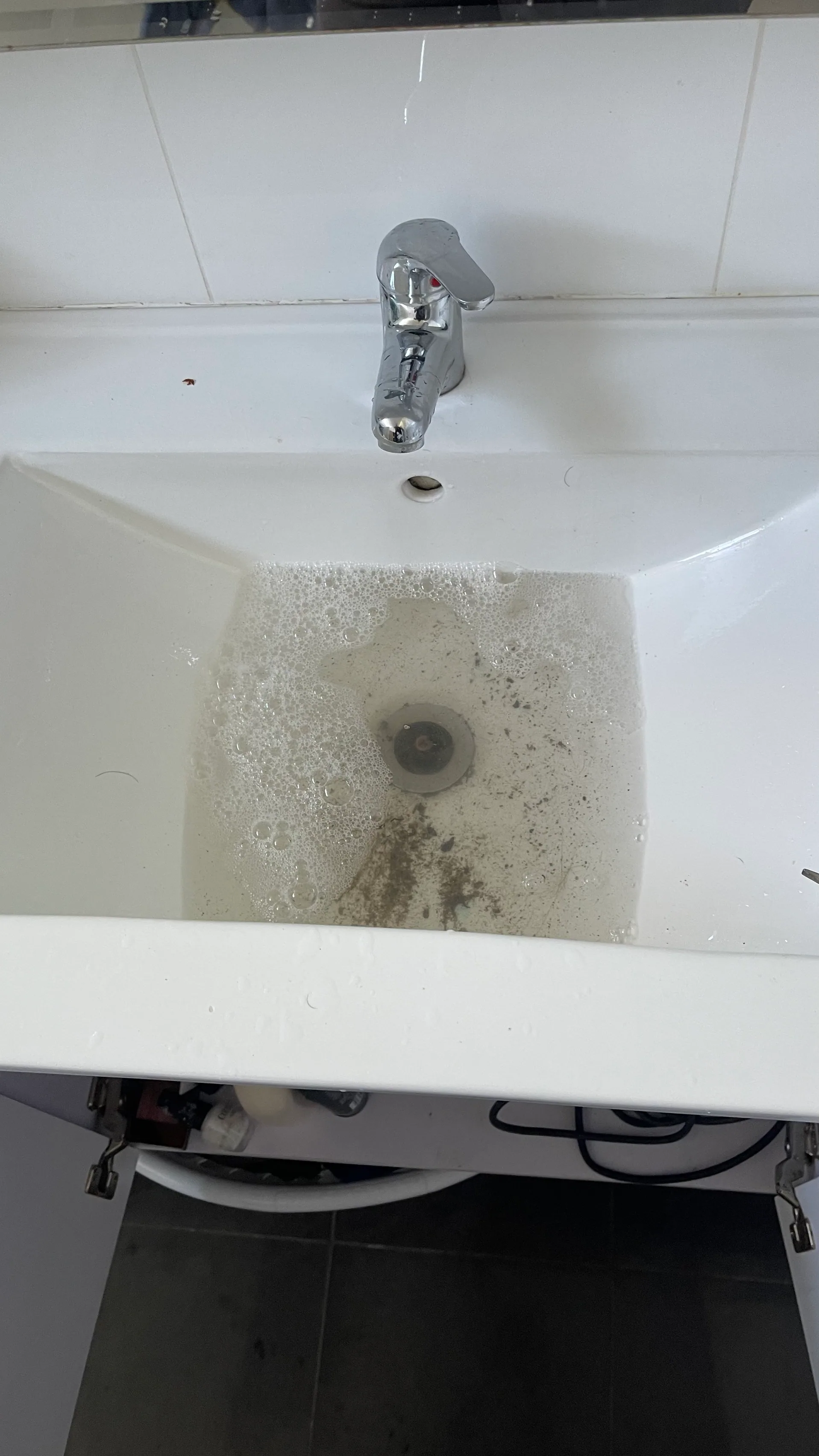 Slow-draining vanity basin with debris around the plug hole